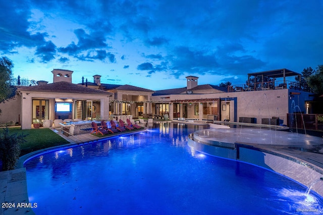 pool at dusk featuring a patio, pool water feature, and an outdoor hangout area