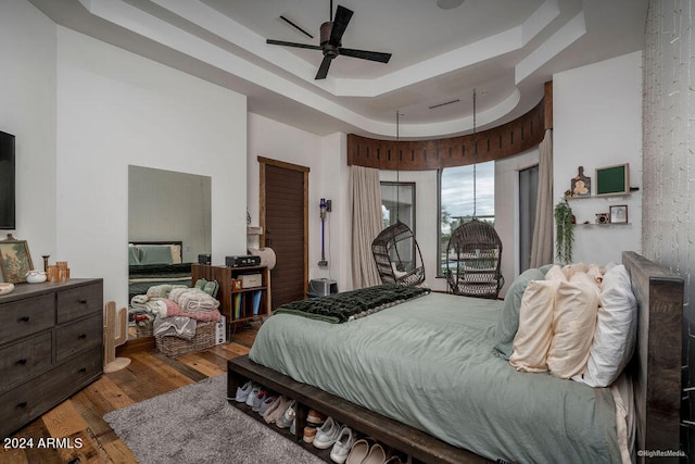 bedroom featuring ceiling fan, wood-type flooring, and a tray ceiling