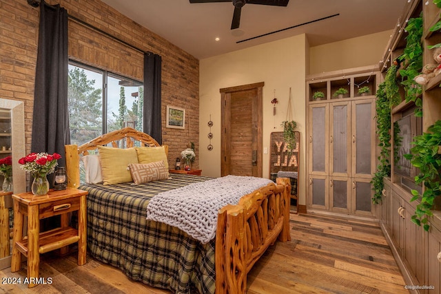 bedroom with ceiling fan, brick wall, and hardwood / wood-style floors