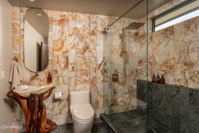 bathroom with tile walls, sink, a shower with shower door, and toilet