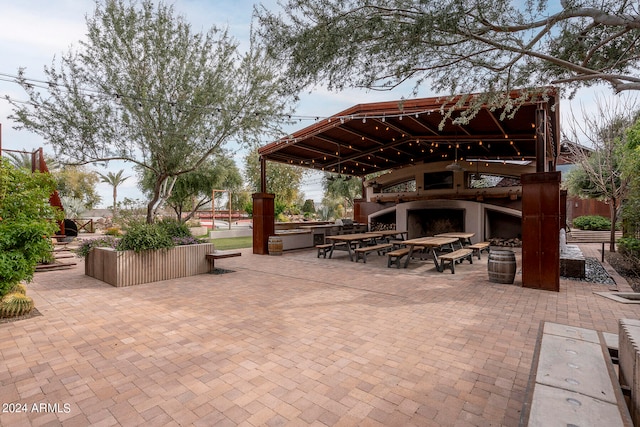 view of patio featuring a gazebo and exterior fireplace