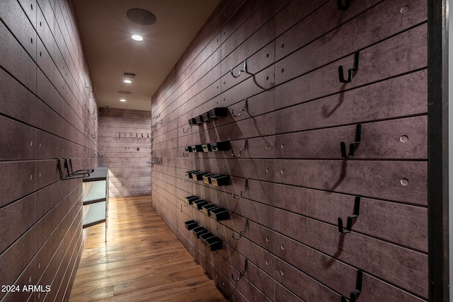 wine room featuring wood walls and light wood-type flooring