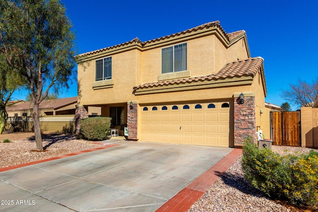 mediterranean / spanish-style house featuring fence, a tile roof, concrete driveway, stone siding, and stucco siding