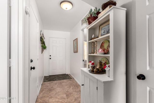 doorway to outside featuring light tile patterned floors and baseboards