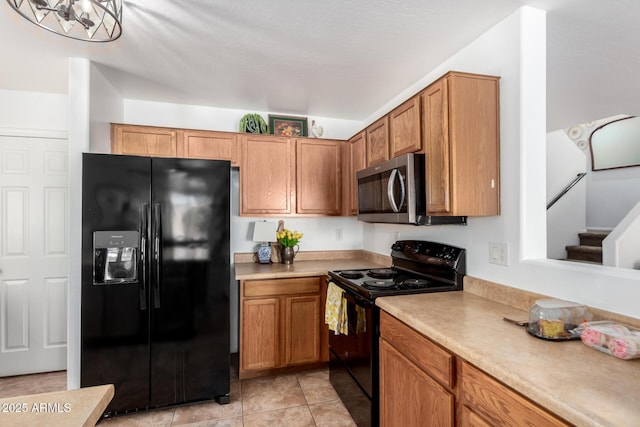 kitchen with light tile patterned floors, black appliances, brown cabinetry, and light countertops