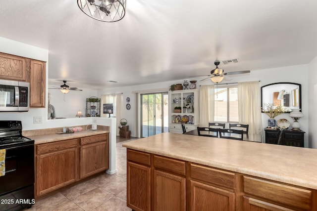 kitchen featuring black range with electric stovetop, visible vents, light countertops, brown cabinetry, and stainless steel microwave