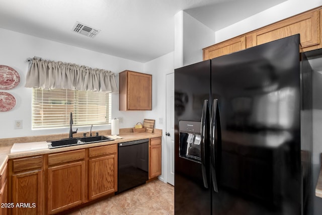 kitchen with light countertops, visible vents, brown cabinetry, a sink, and black appliances