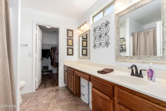 full bath featuring toilet, tile patterned floors, a spacious closet, and vanity