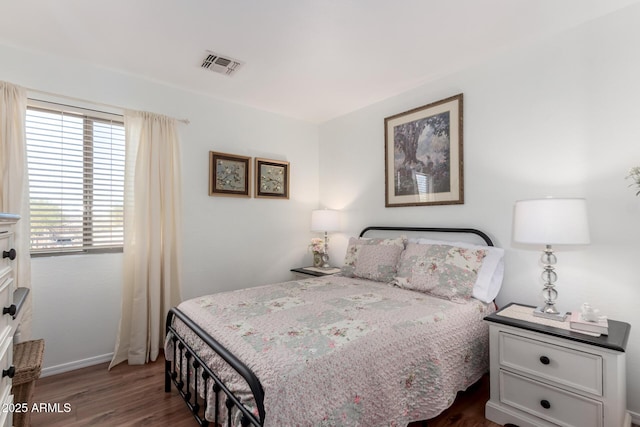 bedroom with dark wood-style floors, visible vents, and baseboards