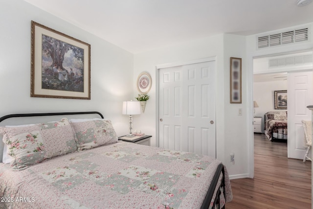 bedroom with dark wood-style flooring, a closet, visible vents, and baseboards