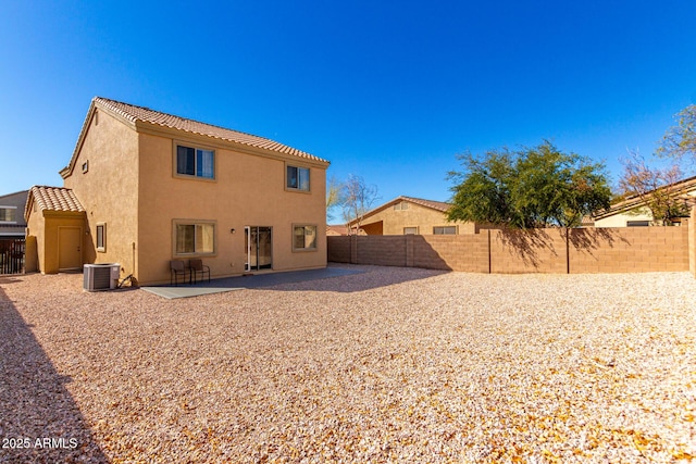 back of property with a patio, a fenced backyard, a tiled roof, central air condition unit, and stucco siding