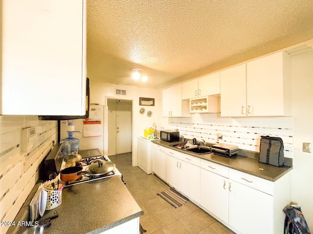 kitchen featuring white cabinets, light tile patterned floors, white refrigerator, and sink