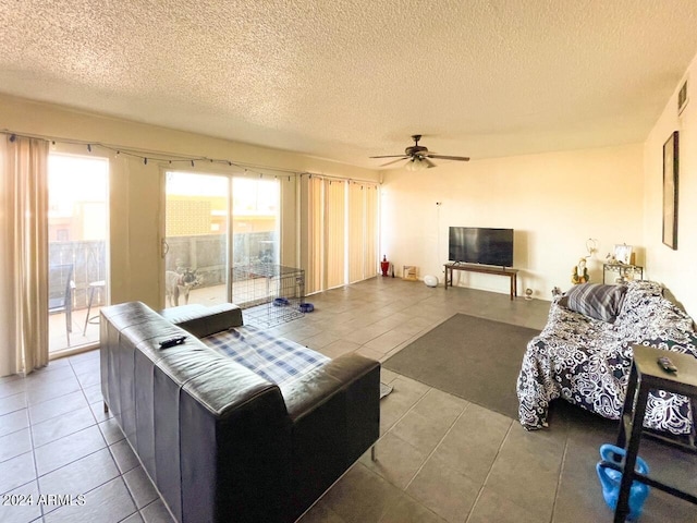 living room with ceiling fan, a textured ceiling, and tile patterned floors