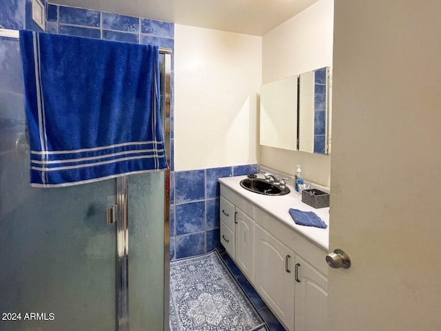 bathroom featuring vanity, tile walls, a shower with shower door, and tile patterned floors