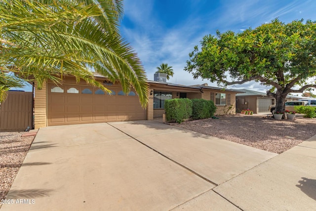 ranch-style house featuring brick siding, fence, a garage, and concrete driveway