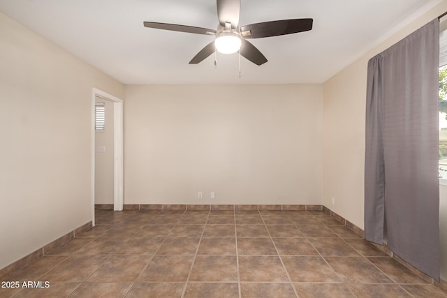 tiled spare room featuring ceiling fan and baseboards