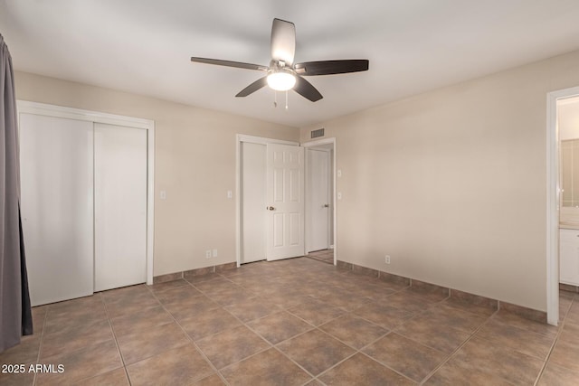 unfurnished bedroom featuring two closets, ensuite bathroom, a ceiling fan, visible vents, and baseboards