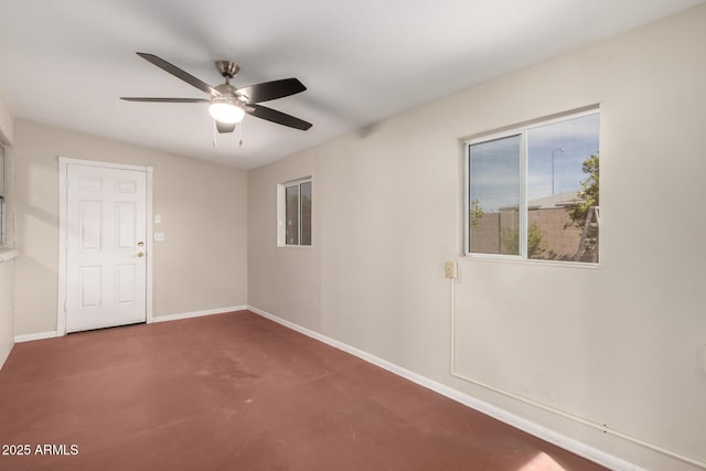 spare room featuring concrete floors, baseboards, and a ceiling fan