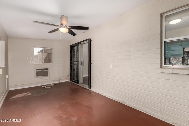 interior space with baseboards, brick wall, an AC wall unit, ceiling fan, and finished concrete floors