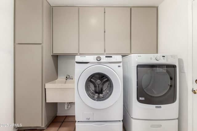 clothes washing area featuring cabinet space, washer and dryer, light tile patterned flooring, and a sink