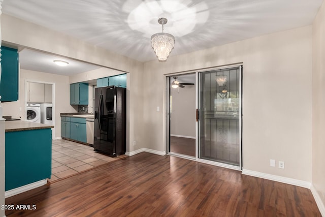 kitchen featuring stainless steel dishwasher, washer / dryer, blue cabinetry, and black fridge