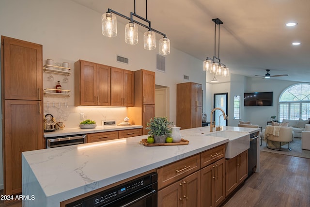 kitchen featuring ceiling fan, sink, dark hardwood / wood-style floors, an island with sink, and decorative light fixtures