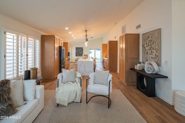 living room featuring light hardwood / wood-style floors, vaulted ceiling, plenty of natural light, and ceiling fan