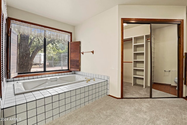 bathroom featuring tiled bath and toilet