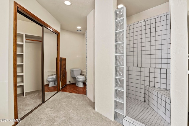 bathroom featuring a tile shower and toilet