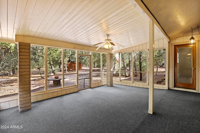 unfurnished sunroom featuring a healthy amount of sunlight, wooden ceiling, ceiling fan, and lofted ceiling