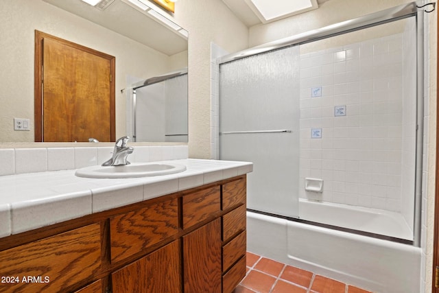 bathroom featuring tile patterned flooring, vanity, and bath / shower combo with glass door