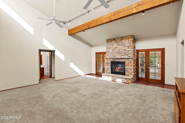 unfurnished living room featuring high vaulted ceiling, french doors, a stone fireplace, beam ceiling, and carpet floors