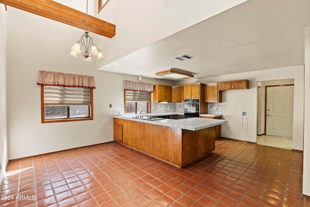 kitchen with kitchen peninsula, tasteful backsplash, black appliances, pendant lighting, and tile patterned flooring