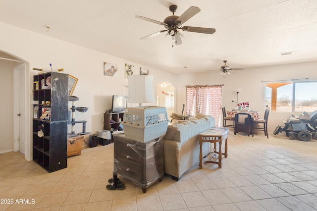 living room featuring arched walkways, ceiling fan, light tile patterned floors, and visible vents