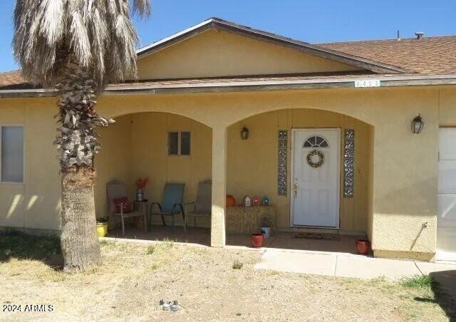 entrance to property with roof with shingles and stucco siding