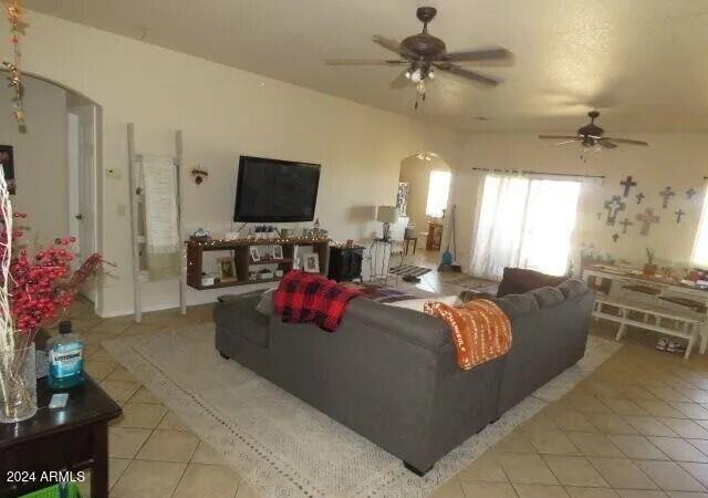 living room featuring light tile patterned floors, arched walkways, and a ceiling fan