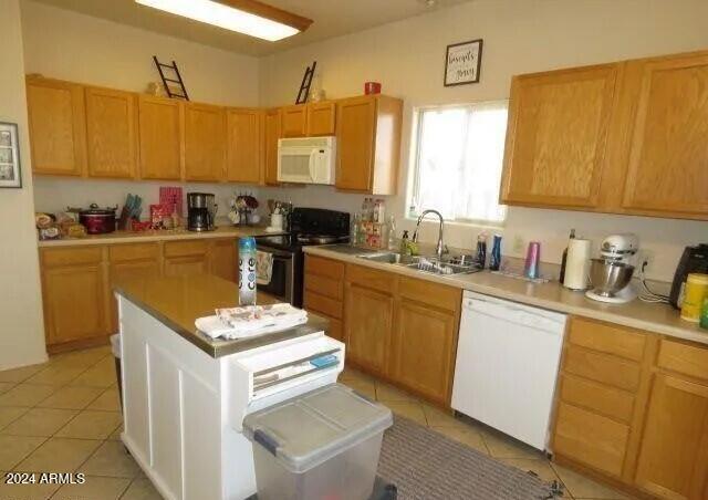 kitchen featuring white appliances, light tile patterned floors, light countertops, and a sink