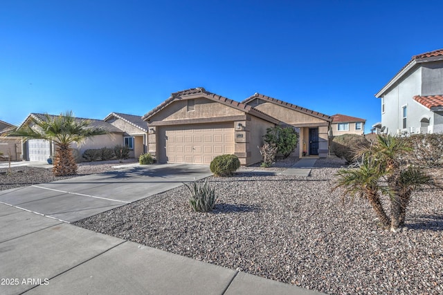 view of front of home featuring driveway, an attached garage, a tile roof, and stucco siding