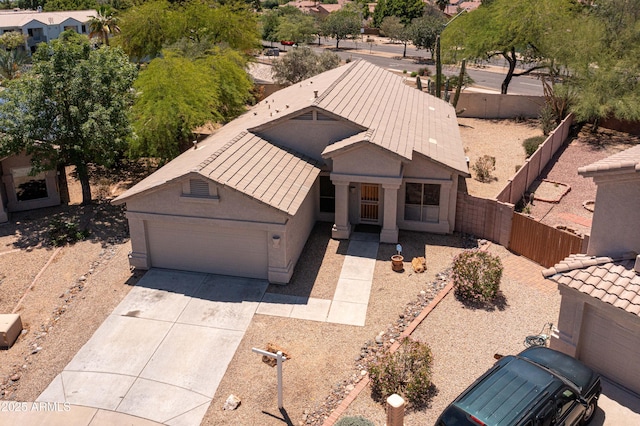 view of front of property featuring an attached garage, concrete driveway, fence, and stucco siding