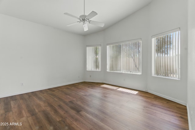 spare room with plenty of natural light, ceiling fan, dark wood-style floors, baseboards, and high vaulted ceiling