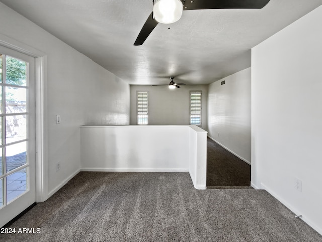 empty room with dark carpet and ceiling fan