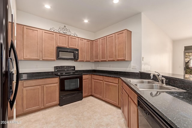 kitchen featuring dark stone countertops, sink, light tile patterned floors, and black appliances