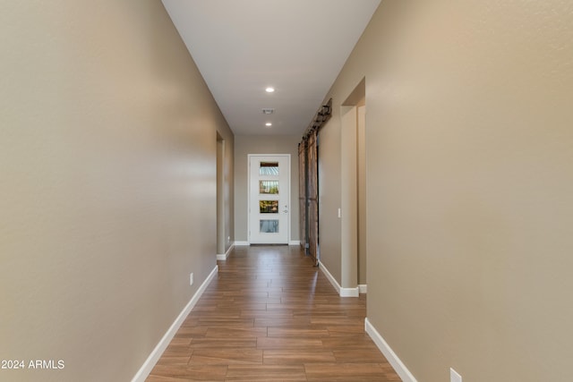 hallway with a barn door and light wood-type flooring