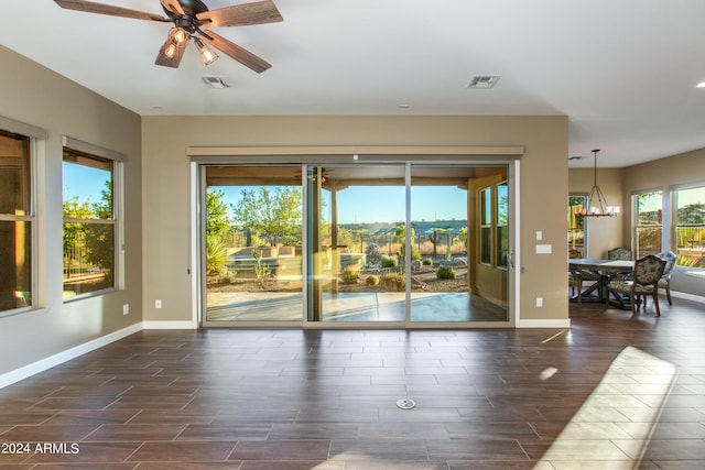 interior space with a healthy amount of sunlight, dark hardwood / wood-style flooring, and ceiling fan with notable chandelier