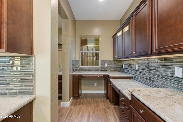 kitchen with light stone counters, light wood-type flooring, and tasteful backsplash