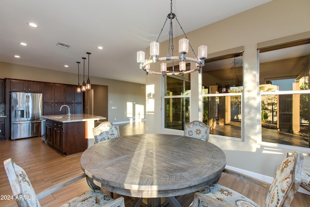 dining room featuring an inviting chandelier, sink, and light wood-type flooring