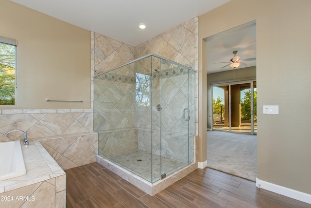 bathroom featuring ceiling fan, plus walk in shower, hardwood / wood-style flooring, and a wealth of natural light