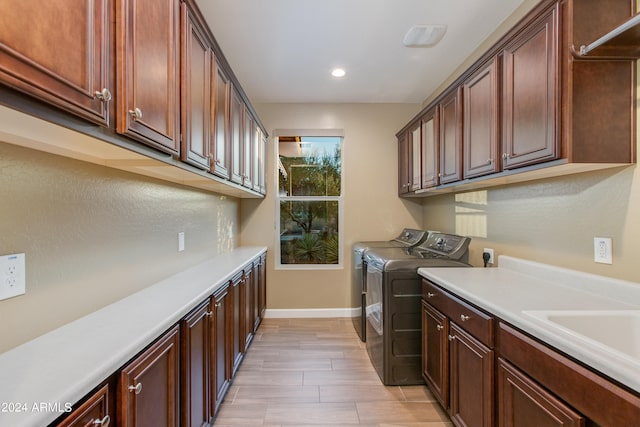 clothes washing area featuring cabinets, light hardwood / wood-style flooring, and washing machine and dryer