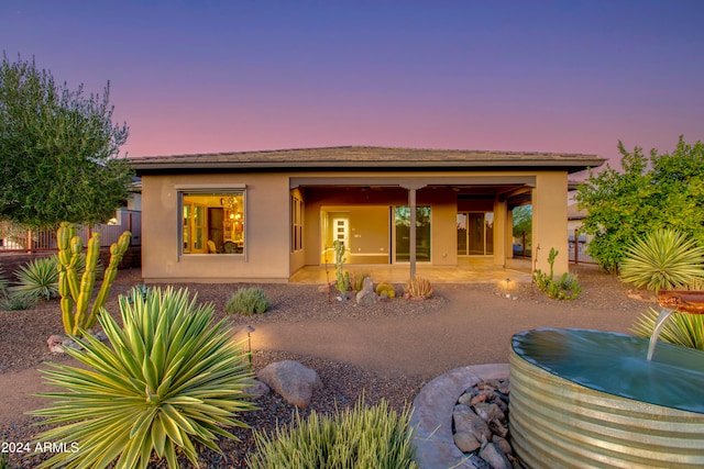 back house at dusk featuring a patio