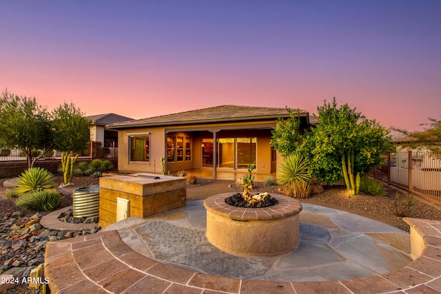 back house at dusk featuring a patio area and a fire pit